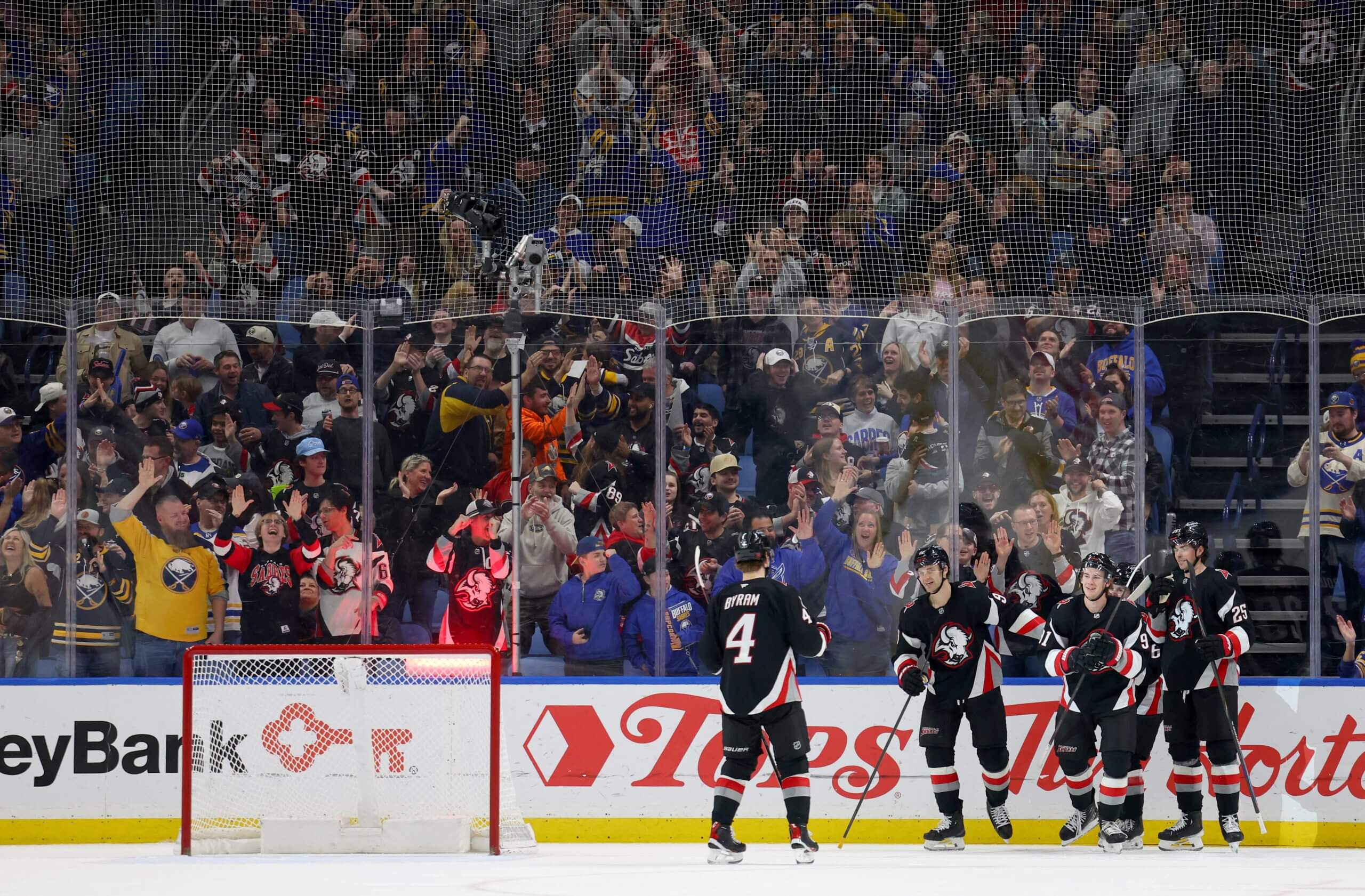 Five Sabres celebrate in front of a raucously cheering crowd and an empty net.